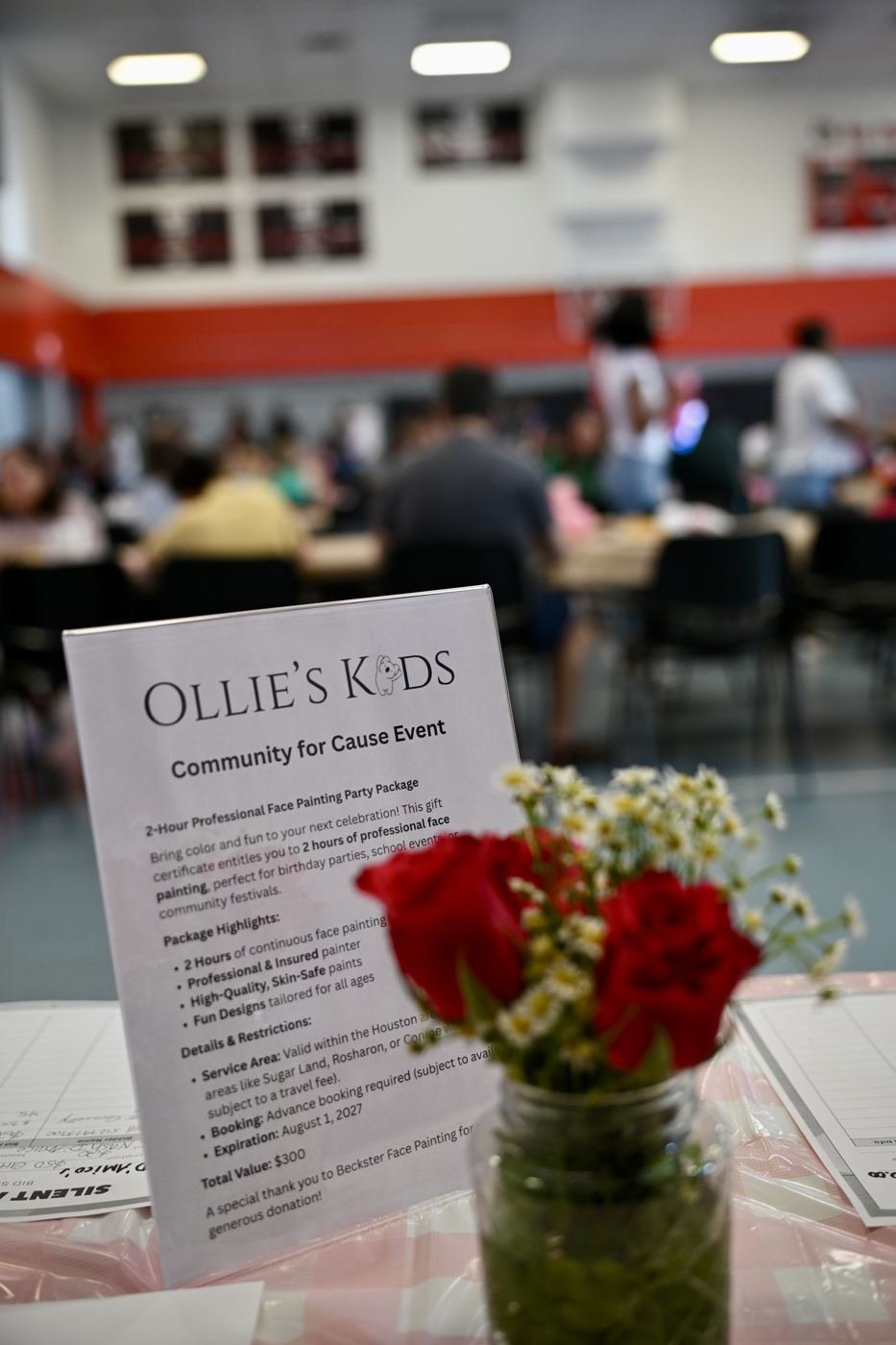 An Ollie's Kids event card and flowers on a table