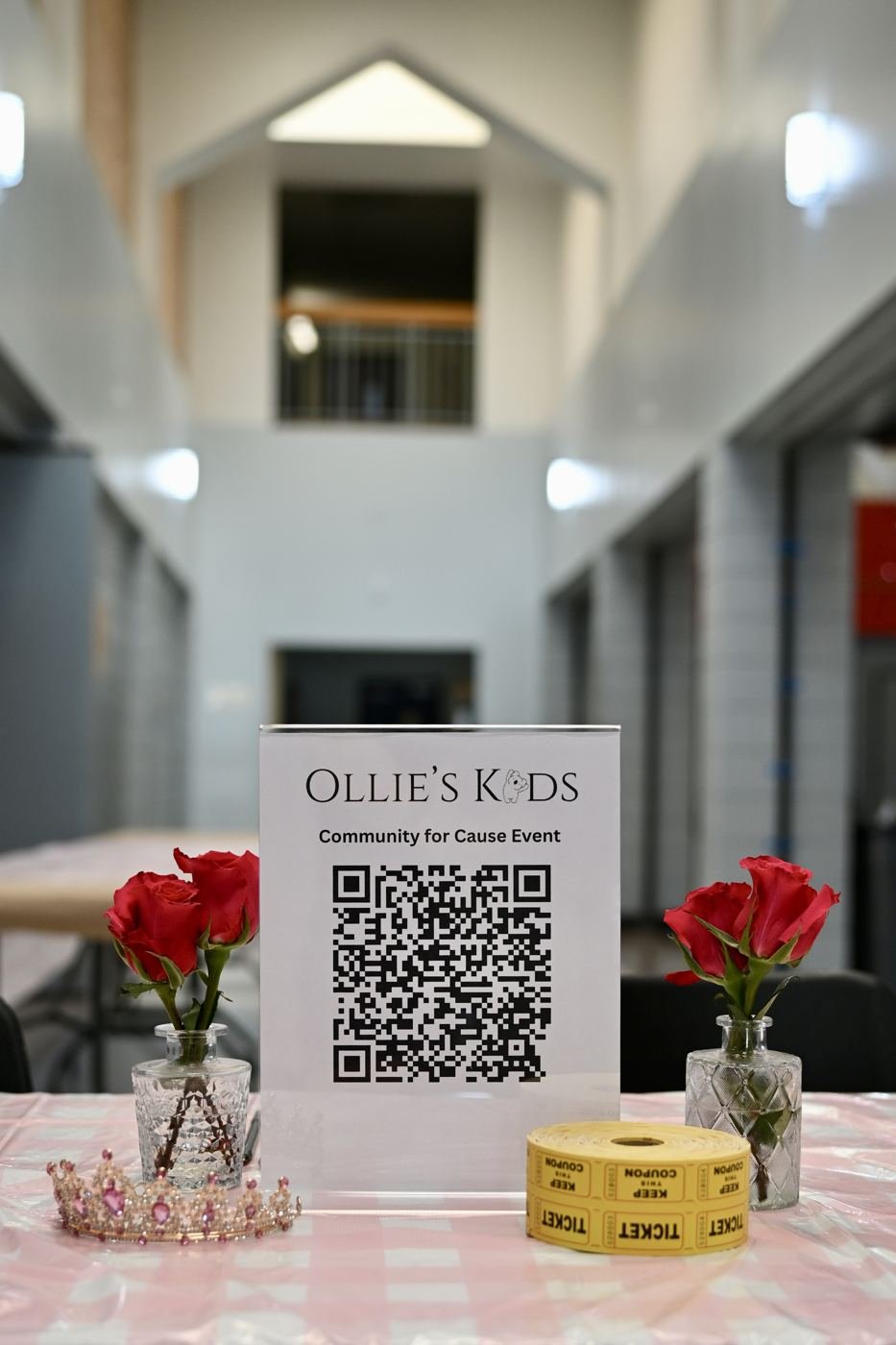 A table centerpiece with flowers, raffle tickets, and a donation code