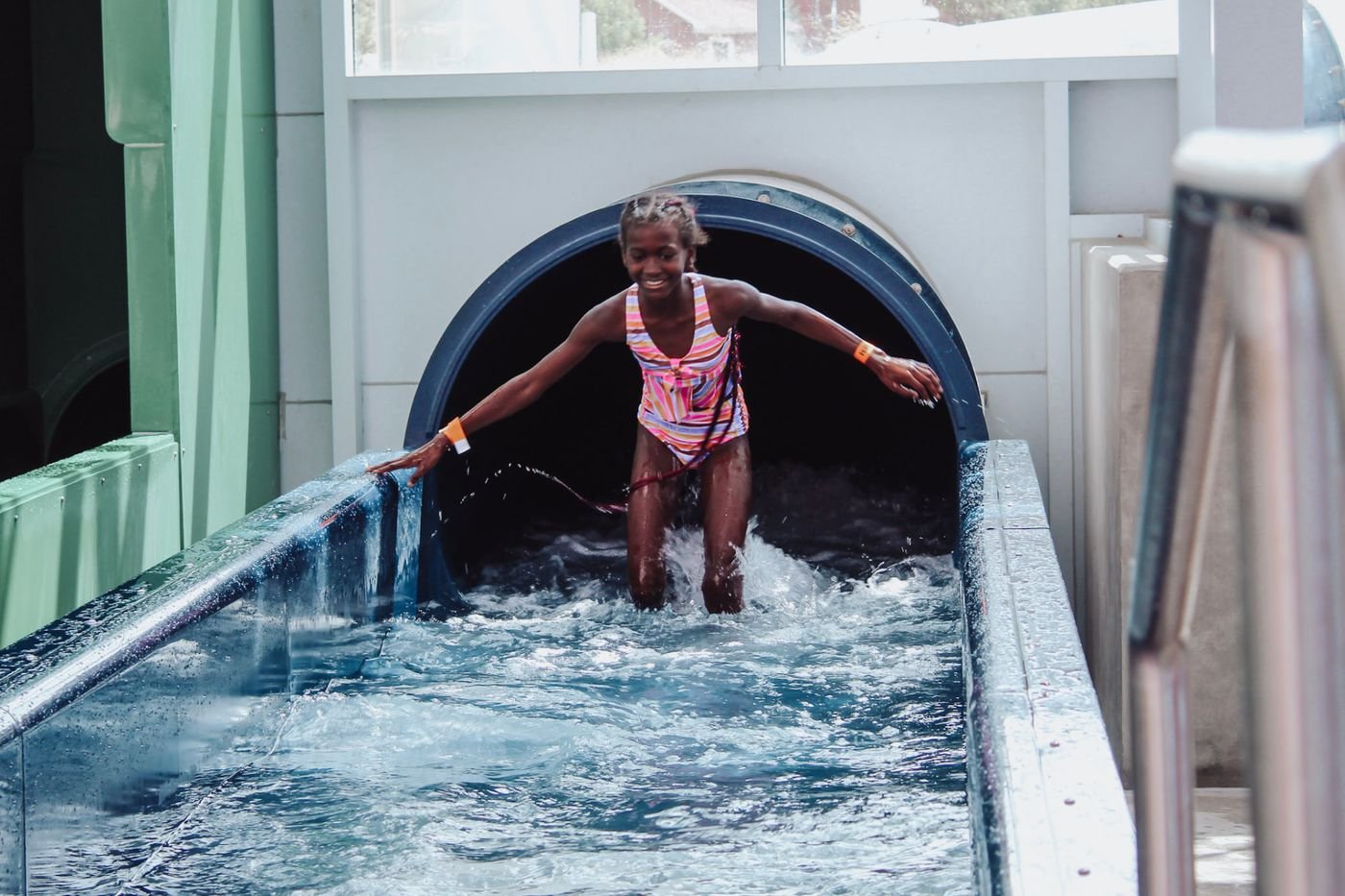 A camper stepping out of a water slide into the splash pool