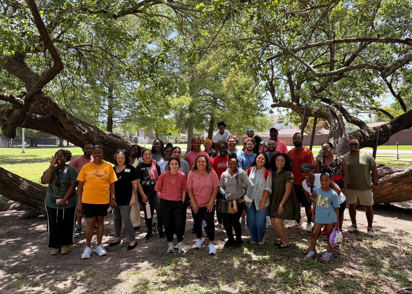 Camp staff and volunteers gathered together under a large shade tree